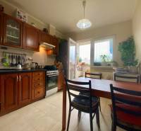 Küche in einer 3-Zimmer-Wohnung mit Holzschränken, Esstisch und Fenster zum Balkon.