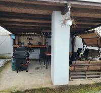 Ein Einfamilienhaus in Tornyosnémeti mit überdachter Terrasse, Grill, Schaukelbank und Essbereich.