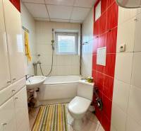 Badezimmer in einer 2-Zimmer-Wohnung mit Badewanne, Waschbecken und weißen Fliesen.