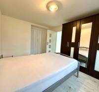 Schlafzimmer in einer 2-Zimmer-Wohnung mit Bett, Schrank und Boden mit Holzdekor.