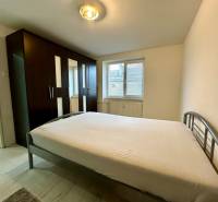 Schlafzimmer mit großem Schrank und Bett in einer 2-Zimmer-Wohnung, heller Boden mit Holzdekor.