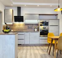 Küche in einer Einzimmerwohnung mit Holzboden, Esstisch und gelben Stühlen.