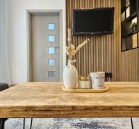 Wohnbereich einer Einzimmerwohnung mit Holztisch und Dekorationen im Hintergrund mit Fernseher.