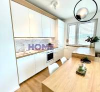 Küche in einer 3-Zimmer-Wohnung mit weißen Schränken und einem Boden in Holzoptik.