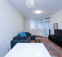 Wohnzimmer einer Zweizimmerwohnung mit Sofa, Fernseher und Holzboden.