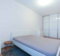 Schlafzimmer in einer 2-Zimmer-Wohnung mit großem Einbauschrank und Boden in Holzoptik.