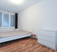 Schlafzimmer in einer 2-Zimmer-Wohnung mit Bett, Kommode und Boden in Holzoptik.