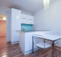 Küche in einer 2-Zimmer-Wohnung mit weißen Schränken und einem Boden in Holzoptik.