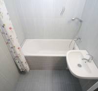 Badezimmer mit Badewanne und Waschbecken in einer 3-Zimmer-Wohnung mit Fliesen.