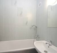 Badezimmer in einer 3-Zimmer-Wohnung mit Badewanne, Waschbecken und Spiegel, helle Fliesen.