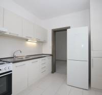 Küche in einer 3-Zimmer-Wohnung mit weißen Schränken und weißem Boden.