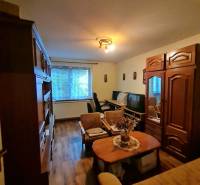 Wohnzimmer in einem Einfamilienhaus mit Möbeln und Boden in Holzoptik.