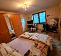 Schlafzimmer mit Bett, Schrank und Tisch in einem Einfamilienhaus.