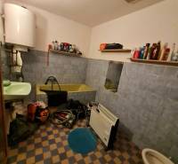 Badezimmer im Einfamilienhaus mit Badewanne, Waschbecken, Regalen und Heizkörper.