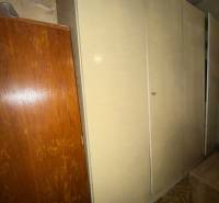 Ein Schrank im Einfamilienhaus, daneben befinden sich braune Möbel und ein Teppich mit geometrischem Muster.