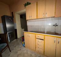 Küche in einem Einfamilienhaus mit Kühlschrank, Schränken und Fliesenboden.