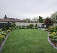 Ein gepflegter Garten mit Terrasse eines Einfamilienhauses in Veľký Grob, reich an Grün und Bepflanzung.