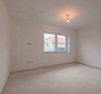 Ein geräumiges Zimmer in einem Einfamilienhaus mit einem Fenster mit Blick auf ein anderes Haus.