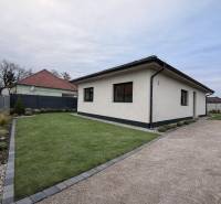 Ein Einfamilienhaus in Veľký Grob mit Rasen, einem Kiesweg und einem gepflegten Garten.