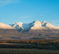 Schneebedeckte Gipfel, herbstliche Landschaft und landwirtschaftliche sowie forstwirtschaftliche Flächen rund um Poprad.