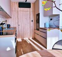 Küche in einer 3-Zimmer-Wohnung mit Holzdekor und eingebauten Geräten.