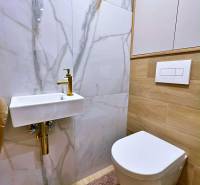 Badezimmer mit Keramikwaschbecken, Spiegel und Boden mit Holzdekor in einer 3-Zimmer-Wohnung.