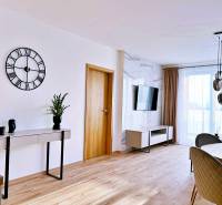 Wohnzimmer in einer 3-Zimmer-Wohnung mit Holzboden, Tisch und Fernseher.