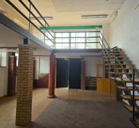 Gewerbeflächen mit Holzboden und Treppe neben Backsteinsäulen.