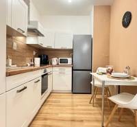 Küche in einer 2-Zimmer-Wohnung mit weißen Schränken und einem Boden in Holzoptik.