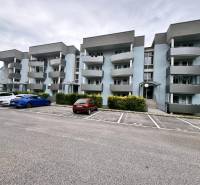 Ein Wohnhaus mit grauen Balkonen in Halalovka in Trenčín mit Parkplätzen.