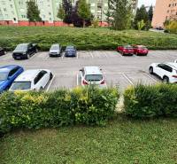 Parkplatz auf Halalovka in Trenčín mit Autos im Hintergrund von Wohnhäusern.