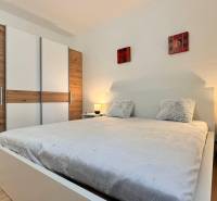 Schlafzimmer in einer 2-Zimmer-Wohnung mit einem großen Bett, einem Kleiderschrank und einem Boden mit Holzdekor.