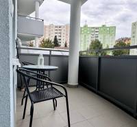 Der Balkon einer 2-Zimmer-Wohnung in Halalovka in Trenčín mit Tisch und Stühlen, Blick auf die Plattenbauten.