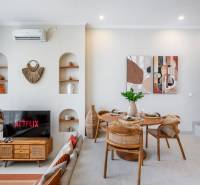 Wohnzimmer der Villa mit Fernseher, Esstisch und dekorativen Elementen an den Wänden.