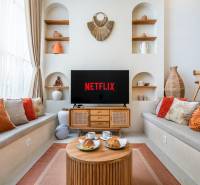 Ein gemütliches Wohnzimmer in einer Villa mit Fernseher, Kissen und Dekorationen, Kaffee wird serviert.