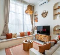 Helles Wohnzimmer in der Villa mit Sofa, Fernseher und dekorativer Beleuchtung.