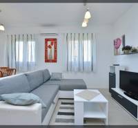 Wohnzimmer in einer 2-Zimmer-Wohnung mit einem bequemen Sofa, weißen Möbeln und einem Fernseher.