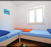 Helles Zimmer mit zwei Einzelbetten und einem Boden in Holzoptik.