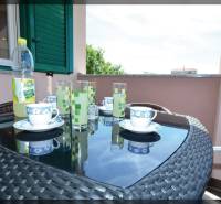 Der Balkon einer 2-Zimmer-Wohnung mit einem Korbtisch, Teeservice und Blick auf Privlaka.