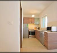 Küche in einer 2-Zimmer-Wohnung mit Holzdekor und Geräten, helle Farben.