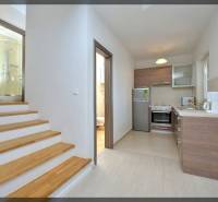 Küche und Treppe mit Holzdekor führen zu einem Badezimmer in einer 2-Zimmer-Wohnung.