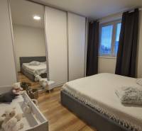 Schlafzimmer in einer 2-Zimmer-Wohnung mit Holzboden, Bett und Kinderbett.