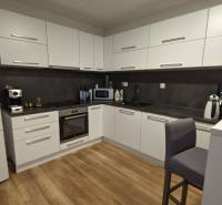 Küche in einer 2-Zimmer-Wohnung mit Holzboden und weißen Schränken.