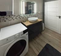 Badezimmer mit Waschmaschine und Waschbecken in einer 3-Zimmer-Wohnung, kleines Mosaik an der Wand.