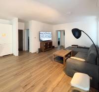 Wohnzimmer in einer 3-Zimmer-Wohnung mit Holzboden und grauem Sofa.