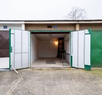 Offene Garage in der Inovecká-Straße in Trenčín mit Innenbeleuchtung und Regalen.