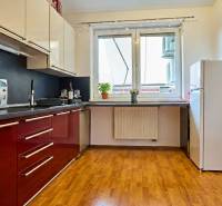 Küche in einer 2-Zimmer-Wohnung mit roten Schränken und einem Boden in Holzoptik.