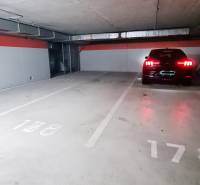 Unterirdische Garage mit Auto, leerem Parkplatz und Betonwänden.