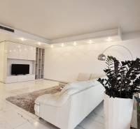 Wohnzimmer in einer 3-Zimmer-Wohnung mit weißem Sofa, Pflanzen und Fernseher auf hellem Boden.