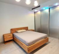 Schlafzimmer mit einem Holzbett, Nachttischen und einem Boden mit Holzdekor in einer 3-Zimmer-Wohnung.